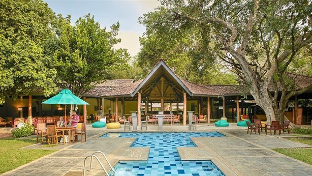 A pool area with two swimming pools, outdoor seating, and a covered pavilion. - Hotel Sigiriya (Dambulla)