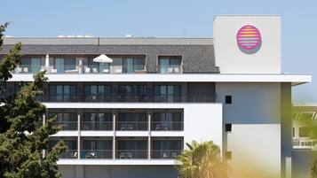 Un hôtel moderne doté d’un toit plat, de nombreux balcons et d’un logo distinctif sur le côté.