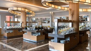 Un moderno vestíbulo de hotel con un mostrador de recepción central, varias estaciones de buffet y un suelo de mármol pulido.