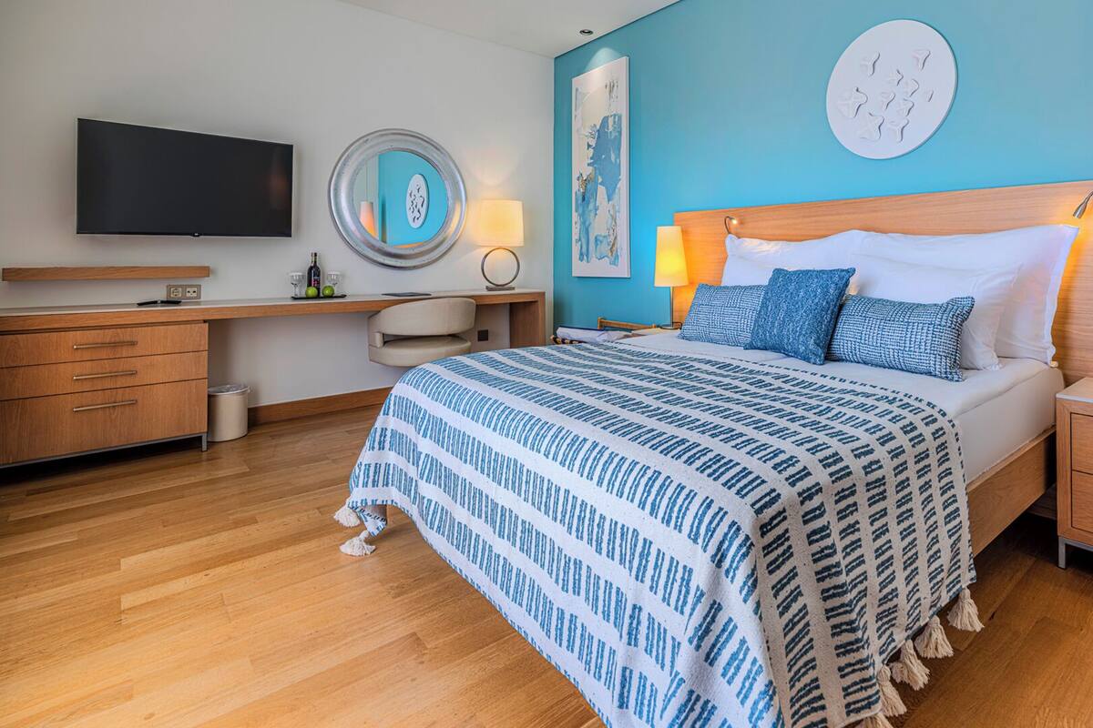 A modern bedroom with a large bed, bedside tables, a desk, and a TV.