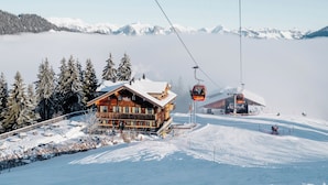 A wooden lodge with a ski lift, surrounded by snow-covered trees and mountains in the background.