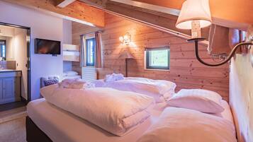 A cozy bedroom with two beds, a TV, a lamp, and a window with curtains.