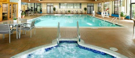 Ein Hallenbad mit Whirlpool, Liegestühlen und einer Dachterrasse.