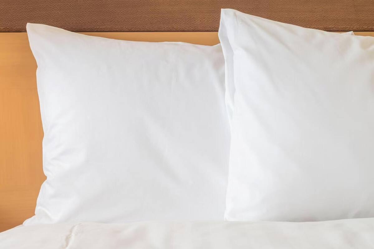 Una cama con ropa blanca y cabecera de madera.