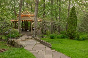 A gazebo with a wooden roof and a stone pathway leading to it.