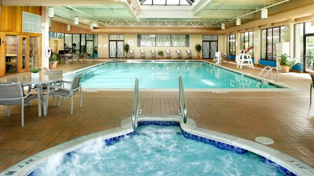 An indoor swimming pool with a hot tub, lounge chairs, and a sunroof. - Doubletree by Hilton Wilkes-barre (Wilkes-Barre)