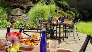 An outdoor dining area with a red umbrella, a table set with food, and chairs. - Doubletree by Hilton Wilkes-barre (Wilkes-Barre)