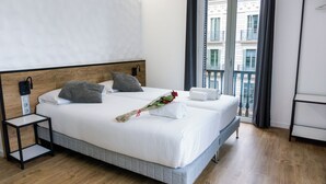 Ein Hotelzimmer mit einem großen Bett, einem Nachttisch und Blick auf einen Balkon.