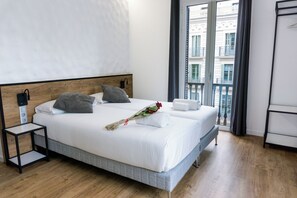 Habitación de hotel con una cama grande, una mesita de noche y vistas a un balcón.