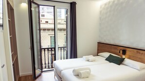 Ein Hotelzimmer mit zwei Betten, einem Balkon und Blick auf Gebäude.