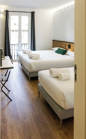 Une chambre d’hôtel avec deux lits, un bureau et un balcon.