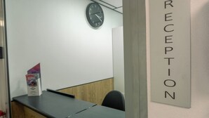 Ein Empfangsbereich mit einer Rezeption, einer Uhr an der Wand und einem Schild, das den Empfang anzeigt.