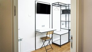 Ein kleines Zimmer mit Schreibtisch, Stuhl und Regalelement.