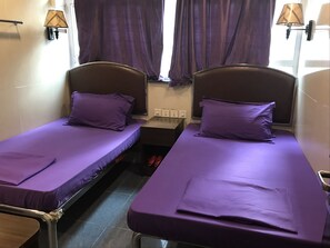 Twin beds with purple bedding, a small table, and a window with curtains. - Paris Guest House (Kowloon)