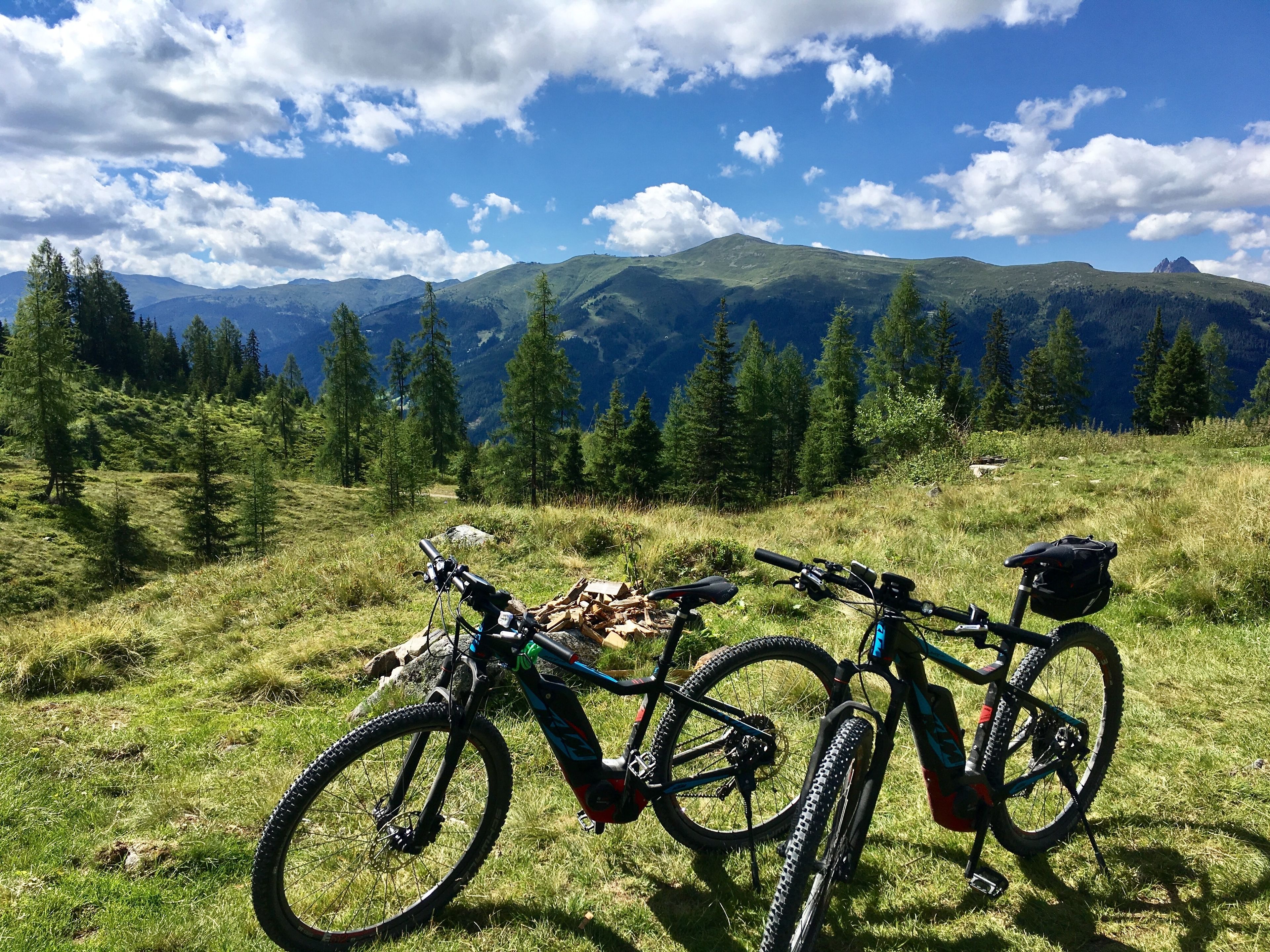 Two bicycles parked on a grassy hill with a mountainous landscape in the background.
