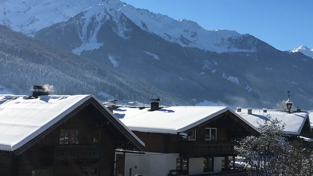 A mountain lodge with snow-covered roofs and a view of snow-capped mountains. - Haus Seifriedsberger (Bramberg am Wildkogel)