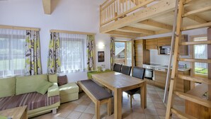 A spacious living area with a wooden dining table, a sofa, and a kitchen in the background. - Haus Seifriedsberger (Bramberg am Wildkogel)