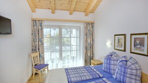 A bedroom with a bed, a chair, a TV, and two framed pictures on the wall. - Haus Seifriedsberger (Bramberg am Wildkogel)
