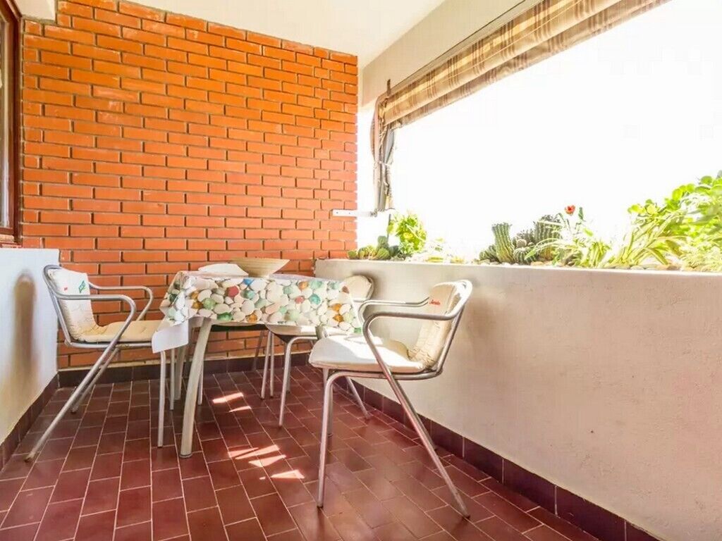 A balcony with a tiled floor, a brick wall, and a table with chairs.