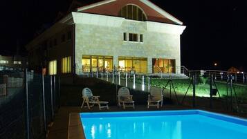 Un hotel con piscina, zona de estar exterior y mostrador de recepción.