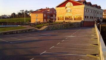 Un hotel con techo rojo, una zona de recepción y un estacionamiento.
