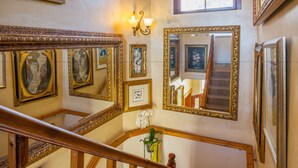 A staircase with ornate railings and multiple framed mirrors on the walls. - Stadium Guest House (Cape Town)