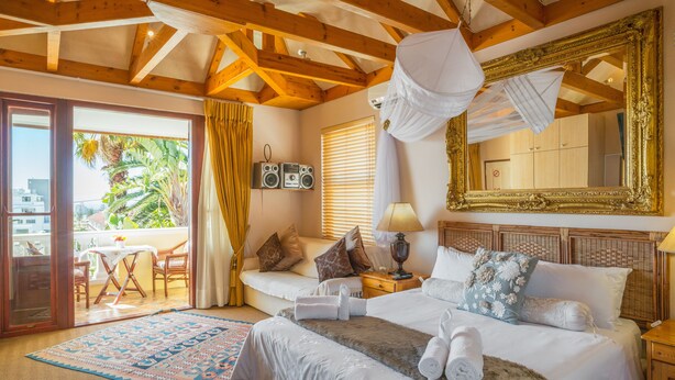 A well-appointed bedroom with a large bed, a balcony with a view, and a classic mirror. - Stadium Guest House (Cape Town)