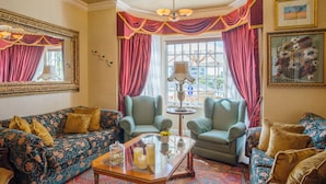 A traditional living room with patterned sofas, a glass coffee table, and a chandelier. - Stadium Guest House (Cape Town)