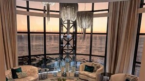 A spacious living room with a large window, a fireplace, and a modern chandelier. - Ocean View Penthouse (Cape Town)