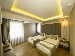 A hotel room with two beds, a desk, a telephone, and a lamp.