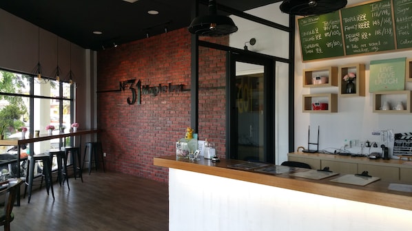 A restaurant interior with a brick wall, wooden tables, and a chalkboard menu.