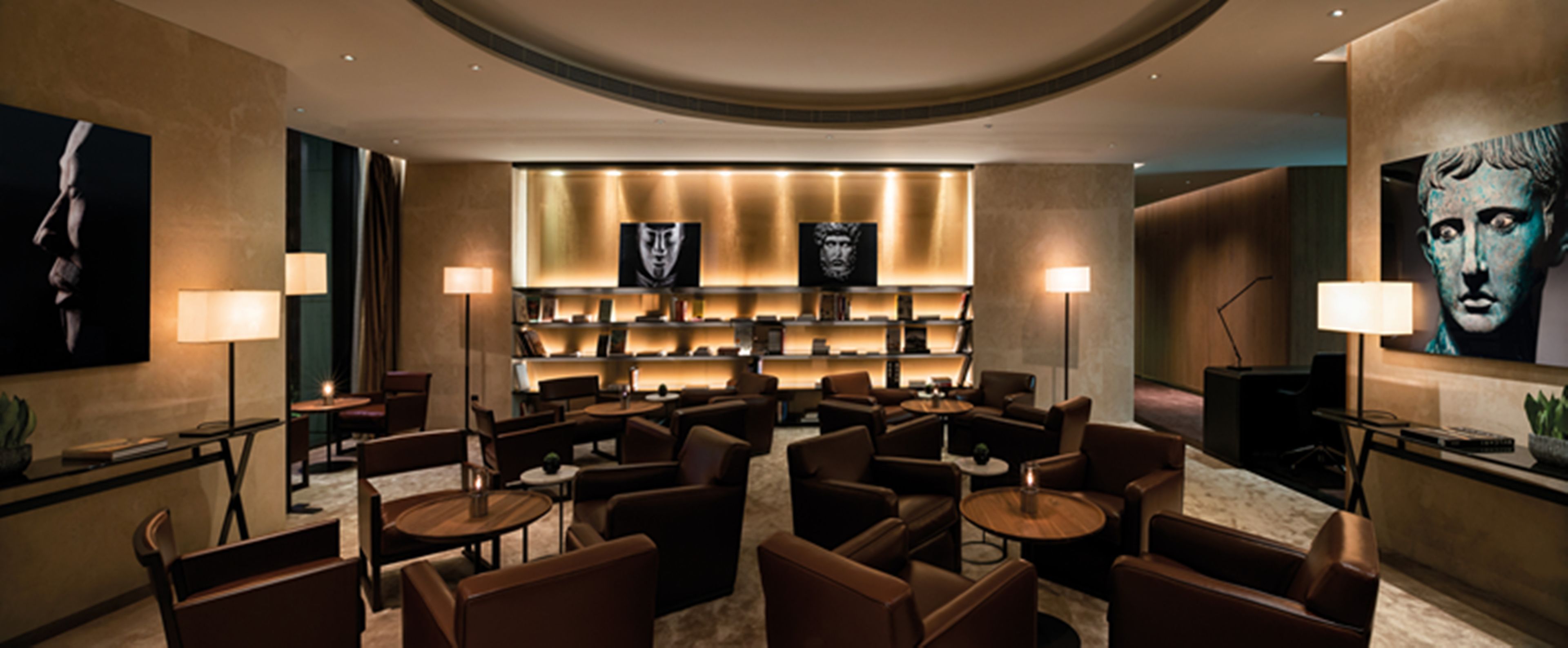 Ein stilvoller Lounge-Bereich mit Sofas, Tischen, einem Bücherregal mit Büchern und Kunstwerken an den Wänden.