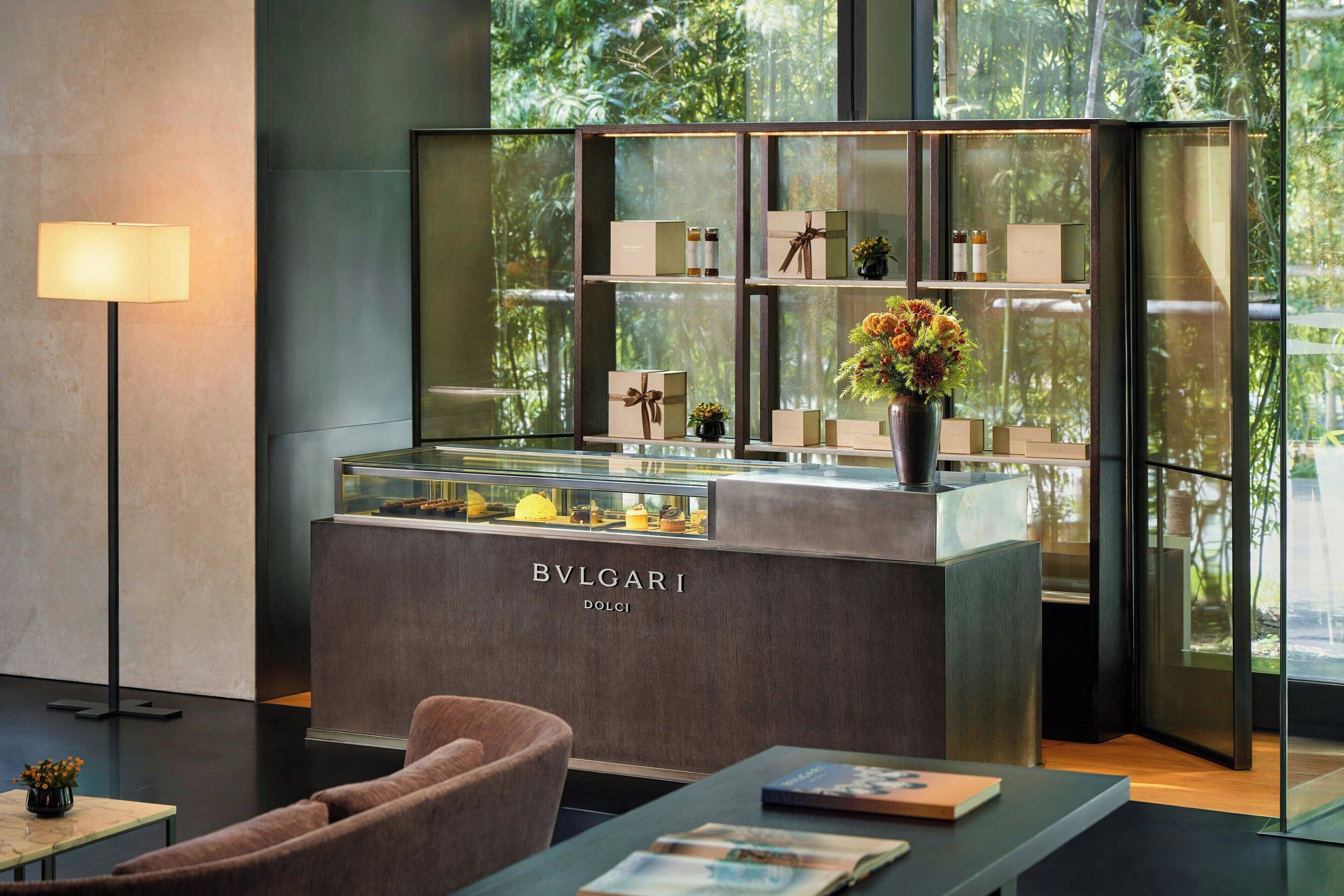 En modern inredning med en utställning av BVLGARI Dolce & Gabbana-produkter, en disk med glasfront och en sittgrupp med en lampa och tidskrifter.