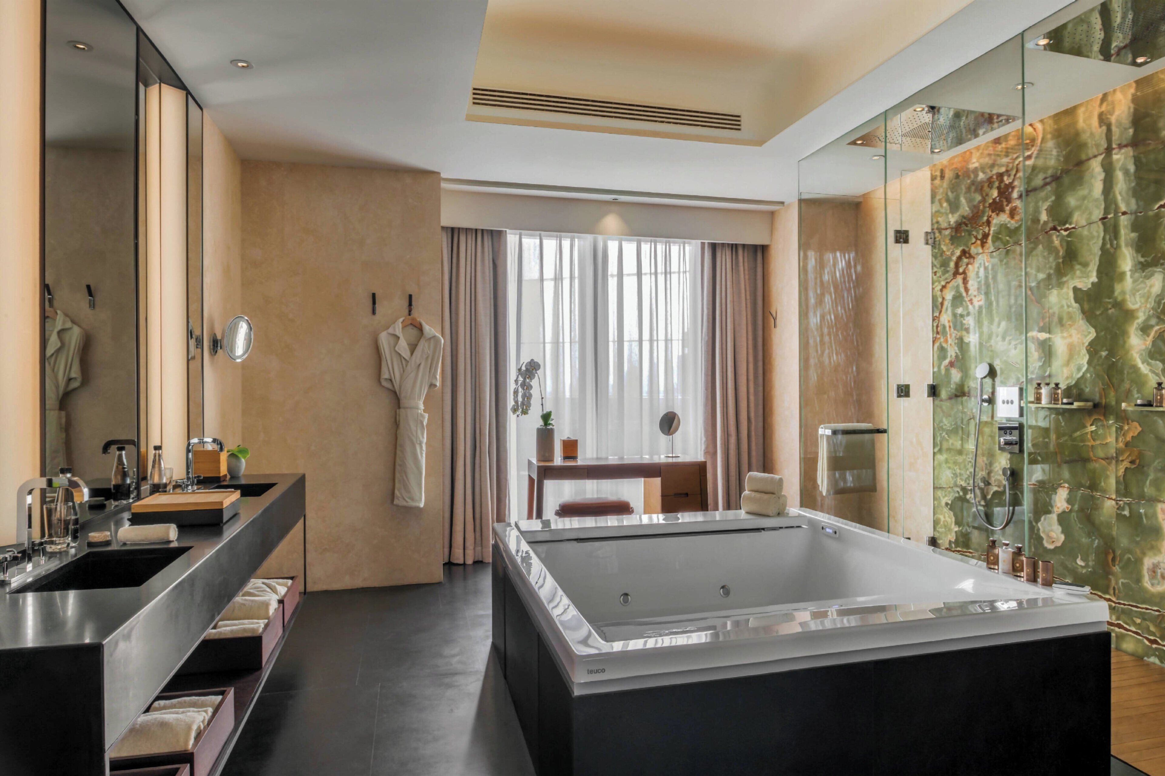 Une salle de bain moderne avec une grande baignoire, un meuble-lavabo à deux vasques et un miroir.