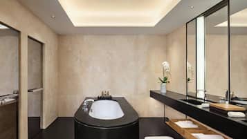 Un bagno moderno con una vasca da bagno nera ampia, uno specchio e un mobile bagno in legno con lavabo.