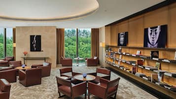 Un vestíbul d'hotel modern amb seients de cuir, una taula de cafè central i una prestatgeria plena de llibres.