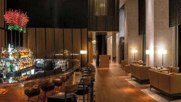 Eine moderne Bar mit einer langen Theke, mehreren Hockern und einer Auswahl an Flaschen.