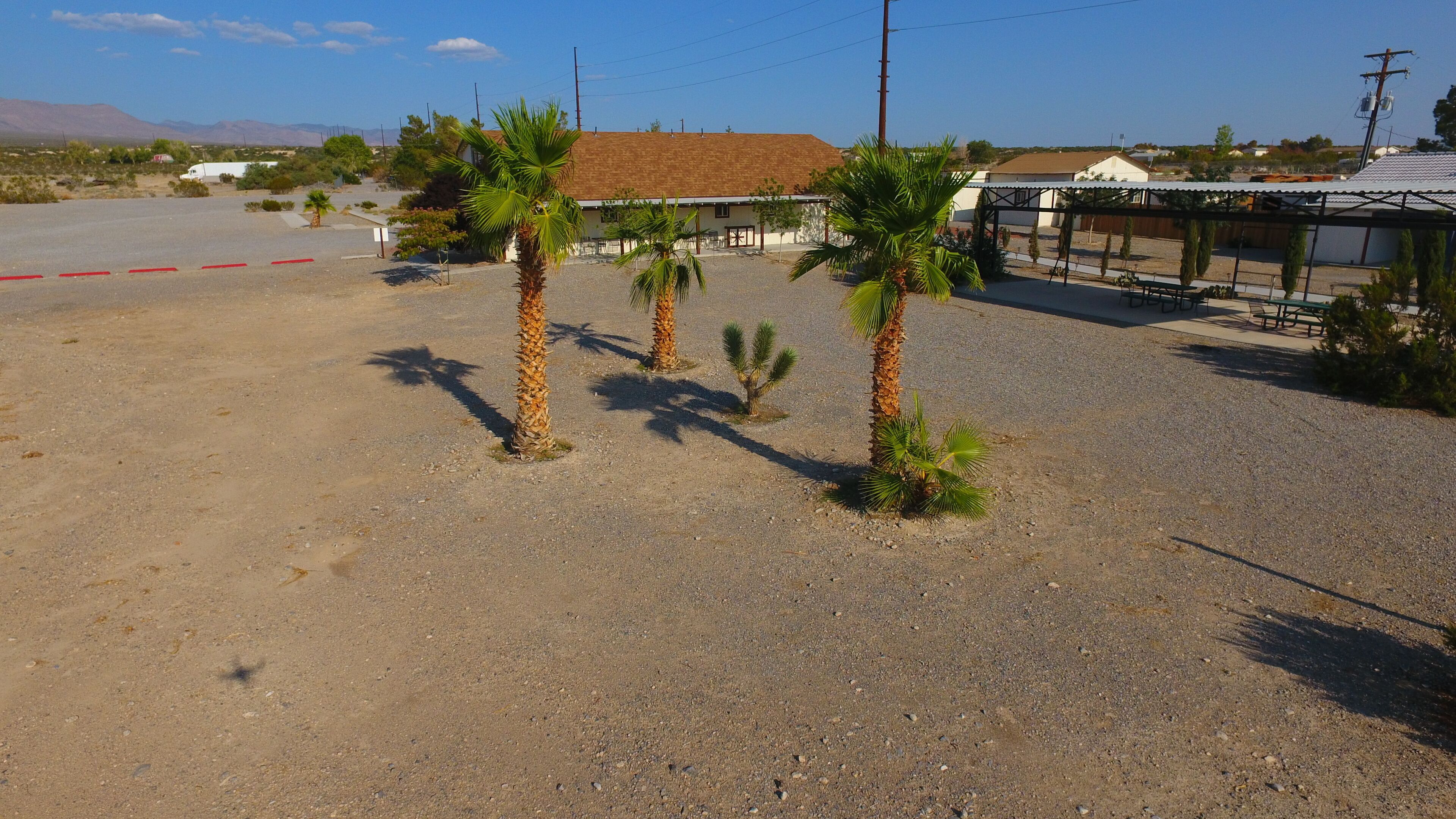A desert landscape with a building that has a brown roof and a fenced area with benches.