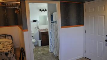 Een slaapkamer met een bed, een badkamer met toilet en een douche.