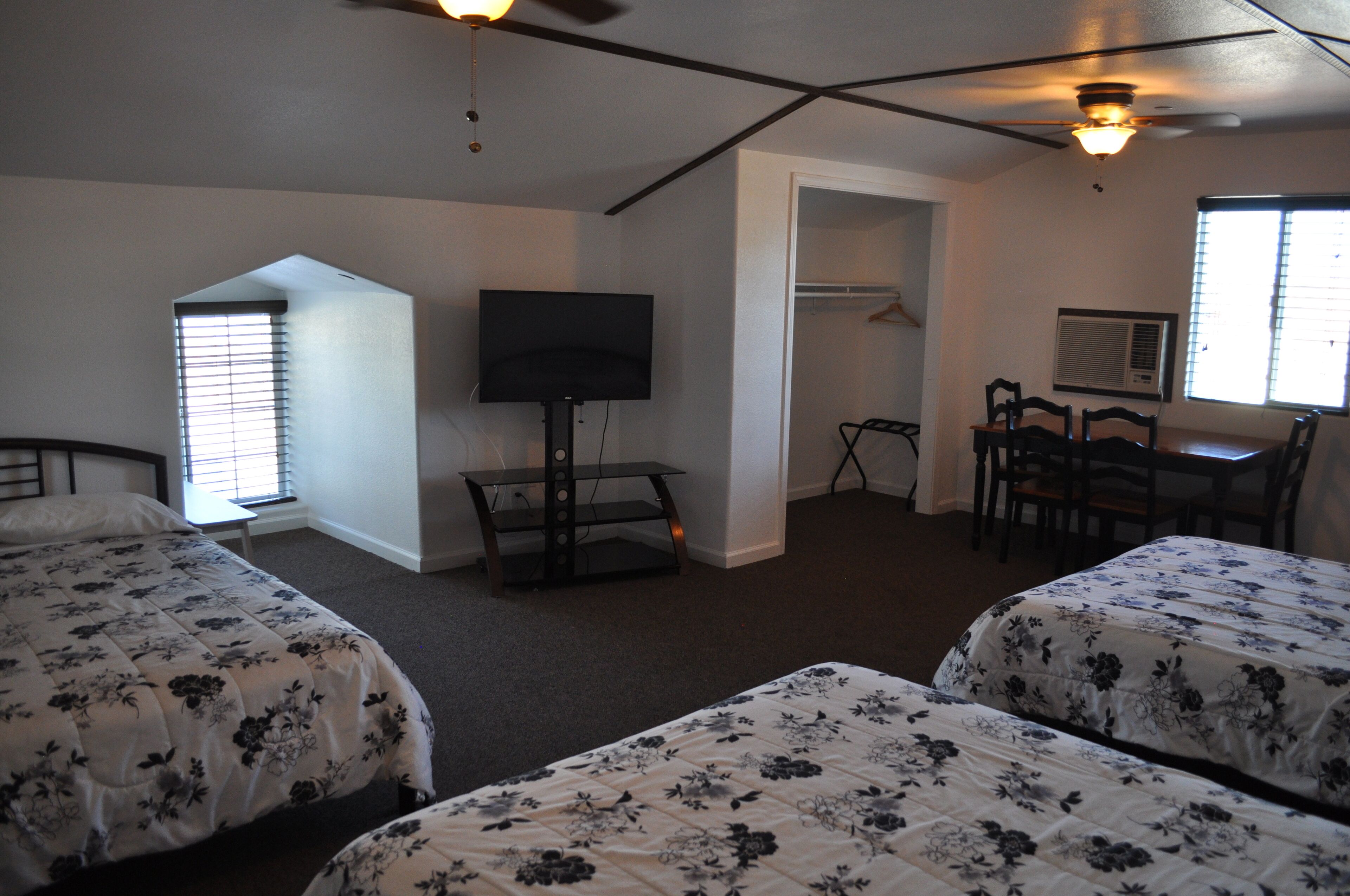 A bedroom with two beds, a TV, a desk, and a chair.