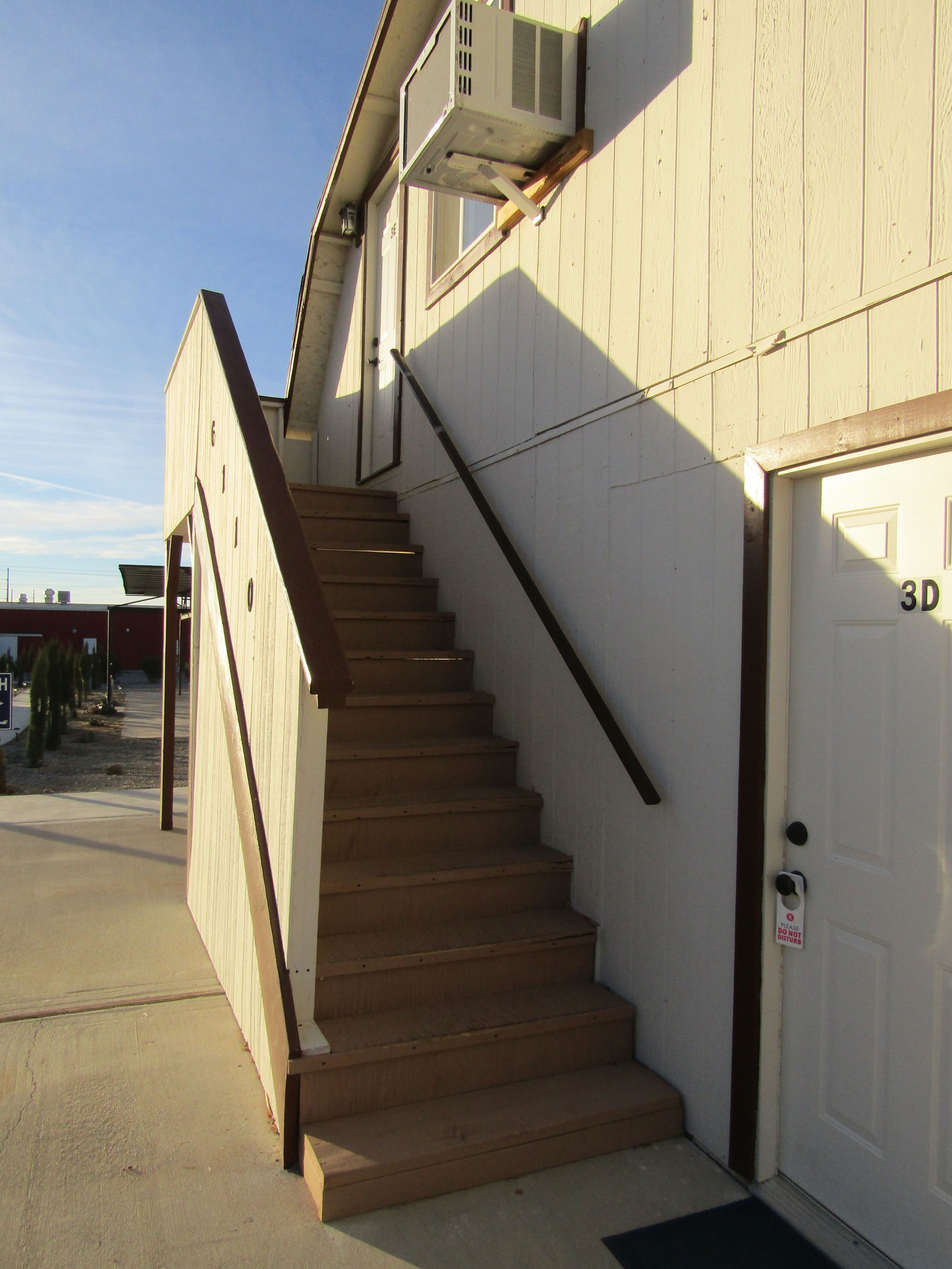 A wooden staircase leading to a white door with a garage number 3D.