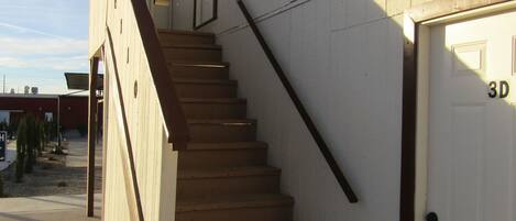 A wooden staircase leading to a white door with a garage number 3D.