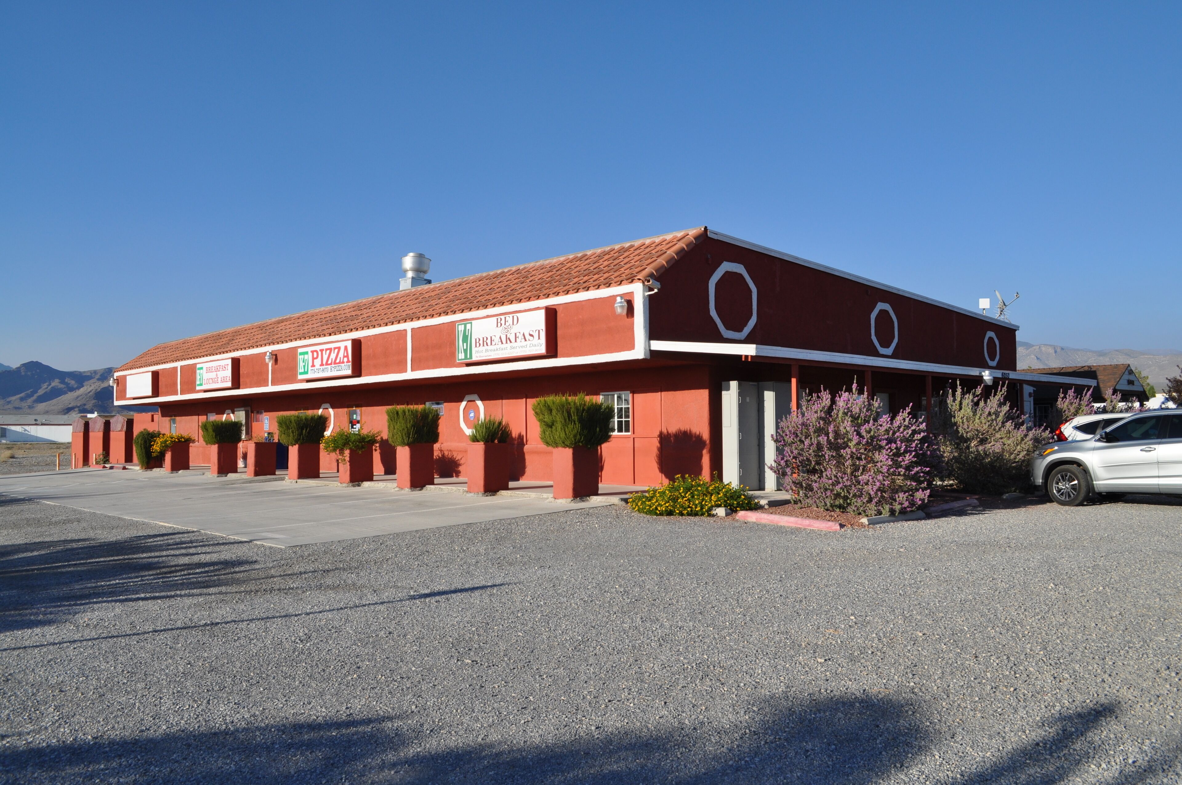 A red building with a sign for a bed and breakfast and a pizza restaurant.