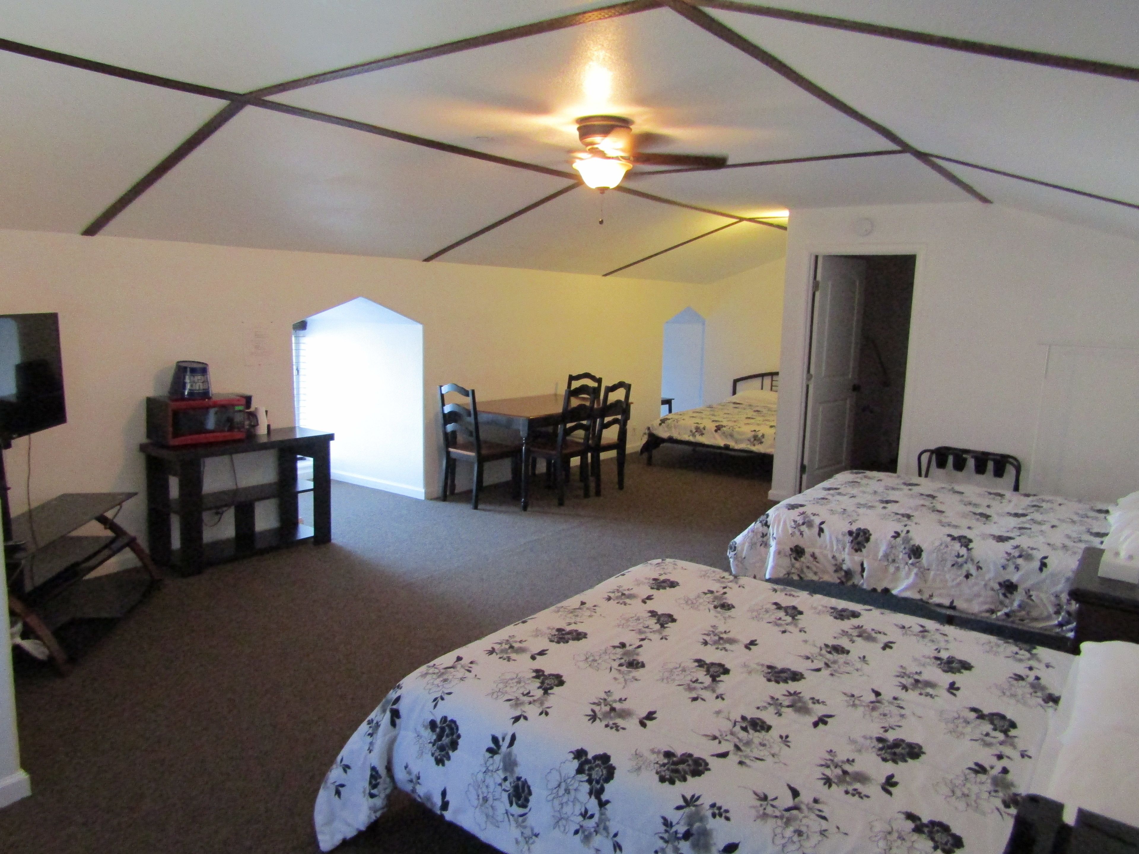 A bedroom with two beds, a desk, and a chair.