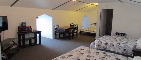 A bedroom with two beds, a desk, and a chair.