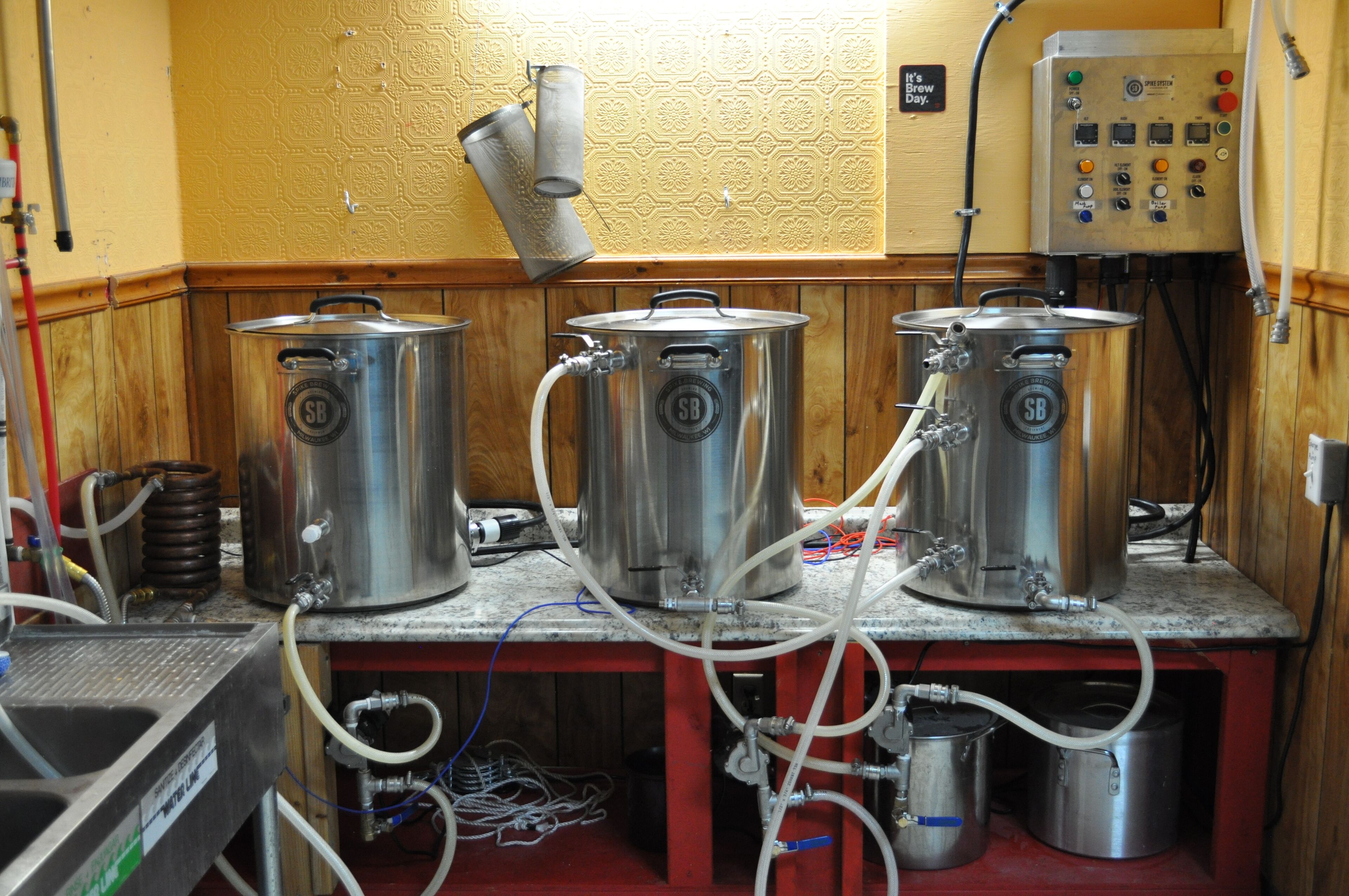 Een keuken met roestvrijstalen kookapparatuur, waaronder pannen en een snelkookpan, verbonden met een bedieningspaneel met diverse knoppen en meters.