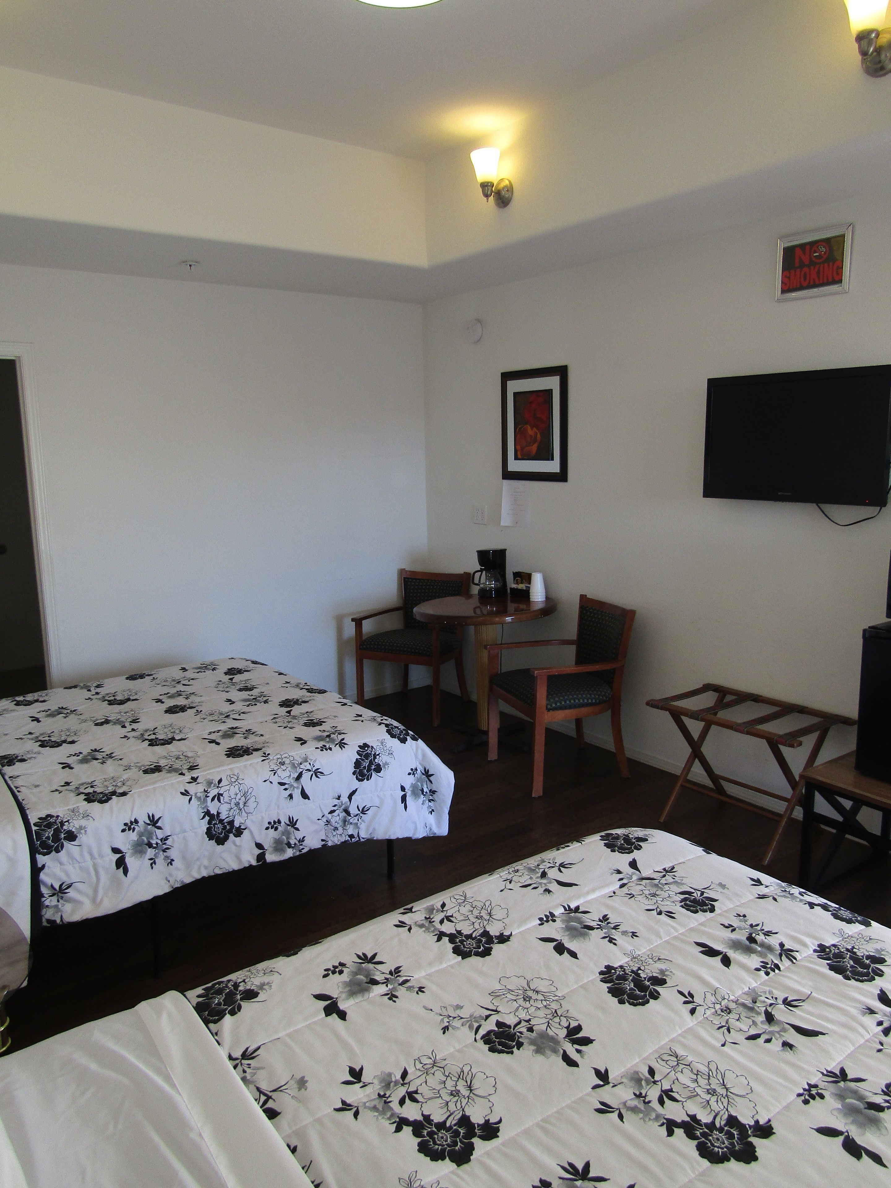 Een hotelkamer met twee bedden, een tafeltje met stoelen, een televisie en een 'Niet roken'-bord.