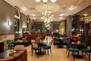 Un hall d’hôtel avec des coins salon, un bar et une cheminée.