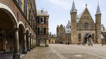 A historic building with a courtyard, arched walkways, and a prominent church with twin spires.