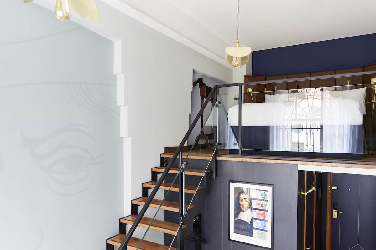 A modern interior with a staircase, a framed picture, and a bed with a canopy.
